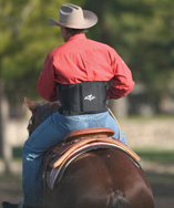 Man on a horse wearing a neoprene back support.